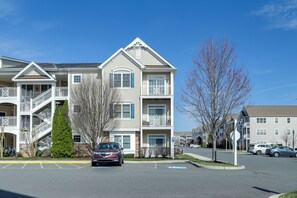 A multi-story residential building with balconies, a parking lot, and a clear blue sky. - 2 Mi to Rehoboth Beach: Updated Condo w/ Pools (Rehoboth Beach)