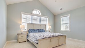 A bedroom with a bed, two nightstands, a window with blinds, and a ceiling fan.