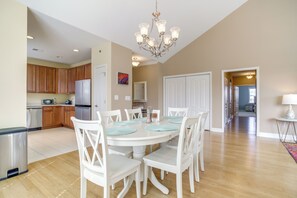 A spacious kitchen with wooden cabinets, a stainless steel refrigerator, and a dining area with a white table and chairs. - 2 Mi to Rehoboth Beach: Updated Condo w/ Pools (Rehoboth Beach)