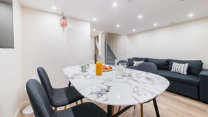 A modern living room with a marble table, black sofas, and a staircase. - Sous Plex palais des congres Porte Maillot - 4P (Neuilly-sur-Seine)