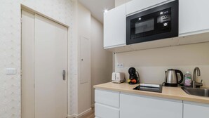 Eine kleine Küche mit Mikrowelle, Toaster, Wasserkocher und Spüle.