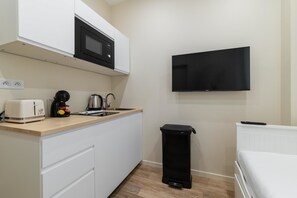 A compact kitchenette with a microwave, toaster, kettle, and sink. A TV is mounted on the wall above the counter. - Sous Plex palais des congres Porte Maillot - 4P (Neuilly-sur-Seine)