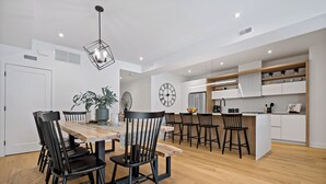 Una cocina moderna con armarios blancos, una mesa de comedor de madera y sillas negras.