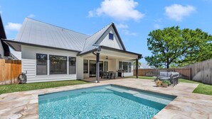 A backyard with a swimming pool, a covered patio, and a house with a sloped roof. - Butterfly:  Luxury w/pool, boat slip, sports court (Kingsland)