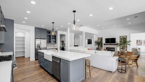A modern kitchen with a central island, built-in appliances, and a dining area with a sofa and chairs. - Butterfly:  Luxury w/pool, boat slip, sports court (Kingsland)