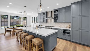 A modern kitchen with grey cabinets, a large island, and bar stools. - Butterfly:  Luxury w/pool, boat slip, sports court (Kingsland)
