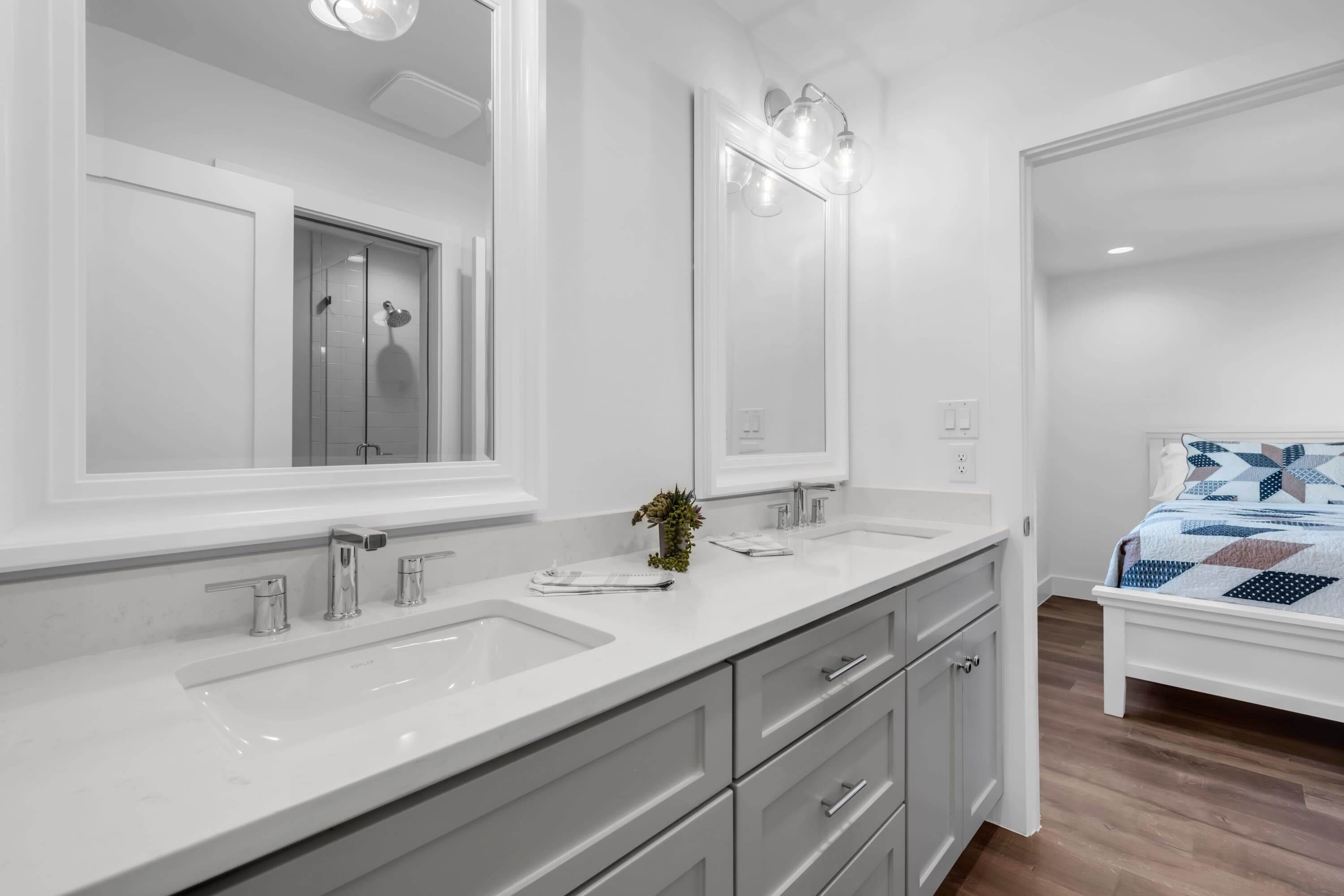 Un baño moderno con dos lavamanos, un espejo grande y una ducha.
