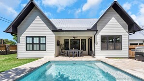 A modern house with a swimming pool, a patio with outdoor furniture, and a covered area with a ceiling fan. - Firefly: Luxury w/pool, boat slip, sports court (Kingsland)