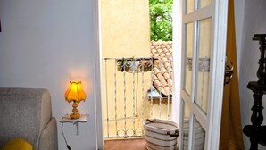 Una habitación con sofá, lámpara, ventana con vista a una zona con baldosas y puerta que da al exterior.