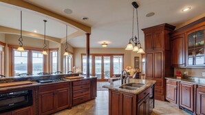 A spacious kitchen with a large island, wooden cabinets, and pendant lighting. - The Villa: hot tub, sauna, game room, theatre (Keuka Park)