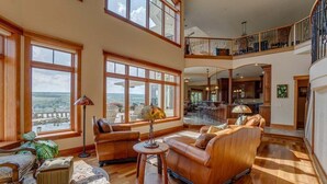 A spacious living area with large windows, a high ceiling, and a view of the outdoors. - The Villa: hot tub, sauna, game room, theatre (Keuka Park)