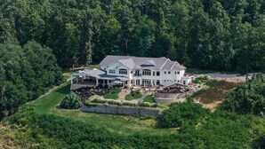 A large, white, two-story house with a spacious patio and a well-maintained garden. - The Villa: hot tub, sauna, game room, theatre (Keuka Park)