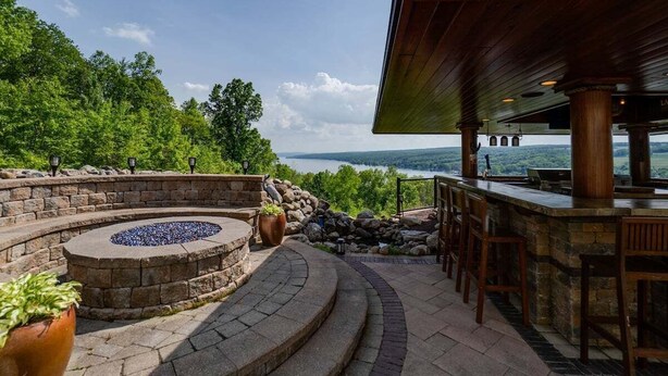 A stone fire pit with seating, a bar area, and a view of a lake. - The Villa: hot tub, sauna, game room, theatre (Keuka Park)