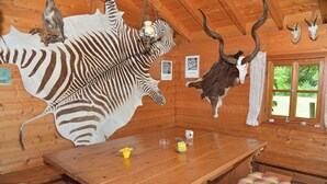 Een houten interieur met een tafel, bankjes en opgehangen dierenkoppen.