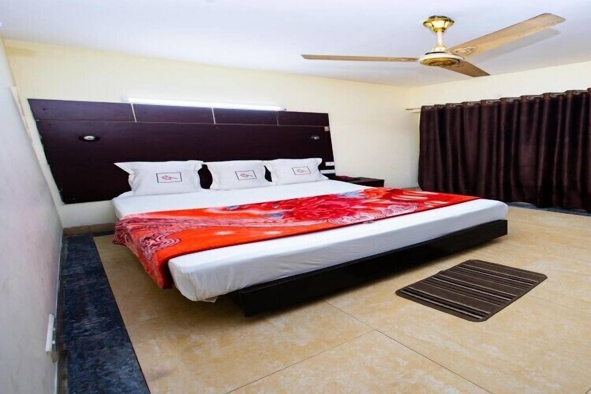 A bedroom with a bed, a ceiling fan, a door, and a window with curtains.