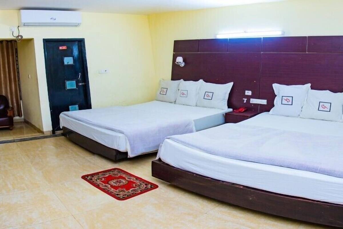 A hotel room with two single beds, a red carpet, a brown leather chair, and a door with a sign.