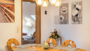 A dining table with a candle centerpiece, wooden chairs, and artwork on the walls. - Holiday Apartment Viola in Schwanau with Private Terrace, Shared Garden and Wi-Fi (Schwanau)