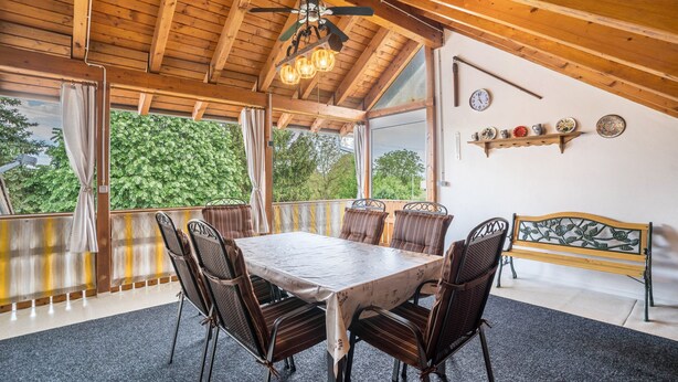 A dining area with a wooden ceiling, a table with chairs, a bench, and a view of greenery outside. - Holiday Apartment Viola in Schwanau with Private Terrace, Shared Garden and Wi-Fi (Schwanau)