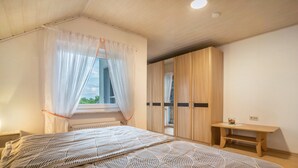 A bedroom with a bed, a window with curtains, a wardrobe, and a small table. - Holiday Apartment Viola in Schwanau with Private Terrace, Shared Garden and Wi-Fi (Schwanau)