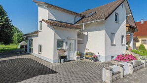A two-story house with a tiled roof, a front door, and a small porch area with a bench and potted plants. - Holiday Apartment Viola in Schwanau with Private Terrace, Shared Garden and Wi-Fi (Schwanau)