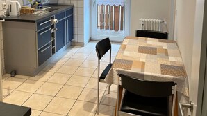 A compact kitchen with a dining area, a radiator, and a door leading to a balcony. - Apartment 'Ferienwohnung Panoramablick' with Mountain View, Shared Terrace and Wi-Fi (Schiltach)