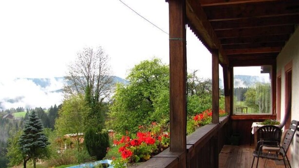 A wooden balcony with a view of a mountainous landscape, a small pool, and a table with chairs. - Apartment 'Ferienwohnung Panoramablick' with Mountain View, Shared Terrace and Wi-Fi (Schiltach)