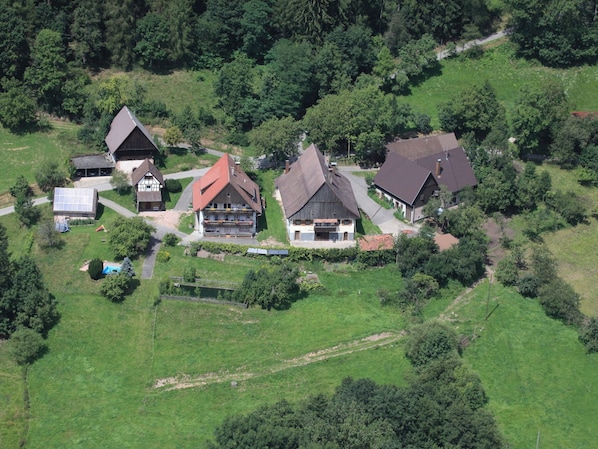 Vue aérienne d’un quartier résidentiel avec des maisons, des champs verdoyants et une petite piscine.