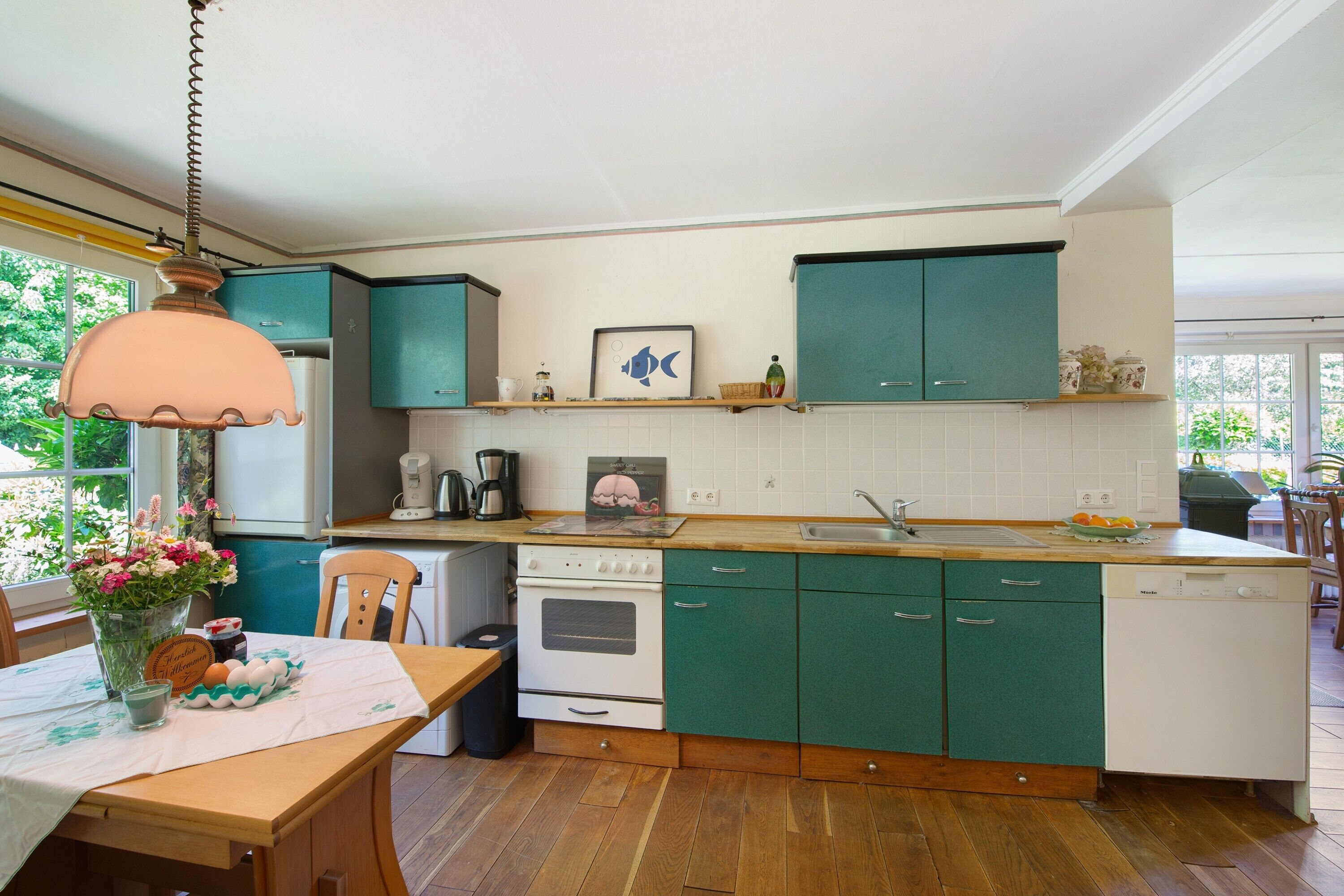 A kitchen with teal cabinets, a wooden countertop, a white stove, and a dishwasher.