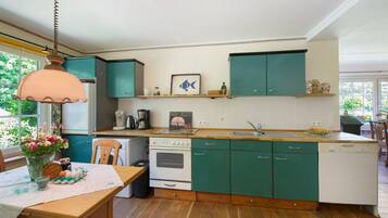 A kitchen with teal cabinets, a wooden countertop, a white stove, and a dishwasher.