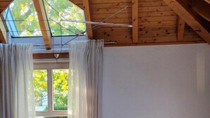 A room with a wooden ceiling, a window with curtains, a lamp, and a sofa with a blanket. - Holiday Home 'Lichtdurchflutetes Architektenhaus' with Mountain View, Terrace and Wi-Fi (Balingen)