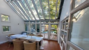 A sunlit room with a glass ceiling, a dining table with chairs, and a view of a garden. - Holiday Home 'Lichtdurchflutetes Architektenhaus' with Mountain View, Terrace and Wi-Fi (Balingen)
