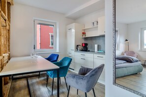 A compact living space with a dining area, kitchenette, and a bed.