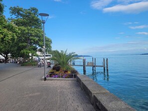 Un paseo marítimo con un camino pavimentado, una farola y un muelle que se adentra en el agua.