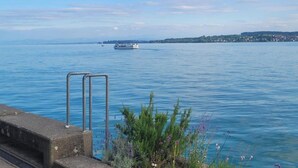 A waterfront view with a boat, a metal railing, and greenery. - Apartment '2 Mit Seeblick' with Lake View and Wi-Fi (Überlingen)