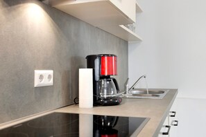 Une cuisine moderne équipée d’une machine à café, d’un porte-essuie-tout et d’un évier en acier inoxydable.