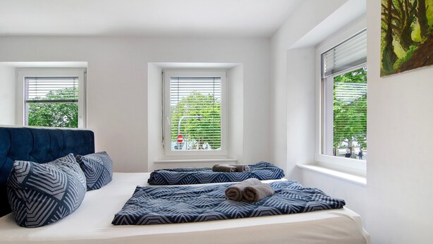 A bedroom with a bed, two windows, and a painting on the wall. - Apartment '1 Mit Seeblick' with Lake View and Wi-Fi (Überlingen)