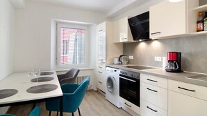 A compact kitchen with a washing machine, oven, and coffee maker. - Apartment '1 Mit Seeblick' with Lake View and Wi-Fi (Überlingen)