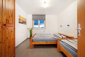 Una camera da letto con due letti in legno, una finestra vista, un termosifone e un armadio in legno.