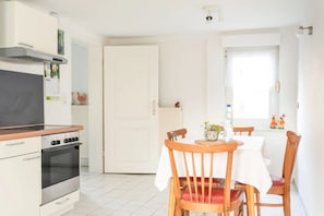 Eine Küche mit Herd, Backofen und einem Esstisch mit Stühlen.