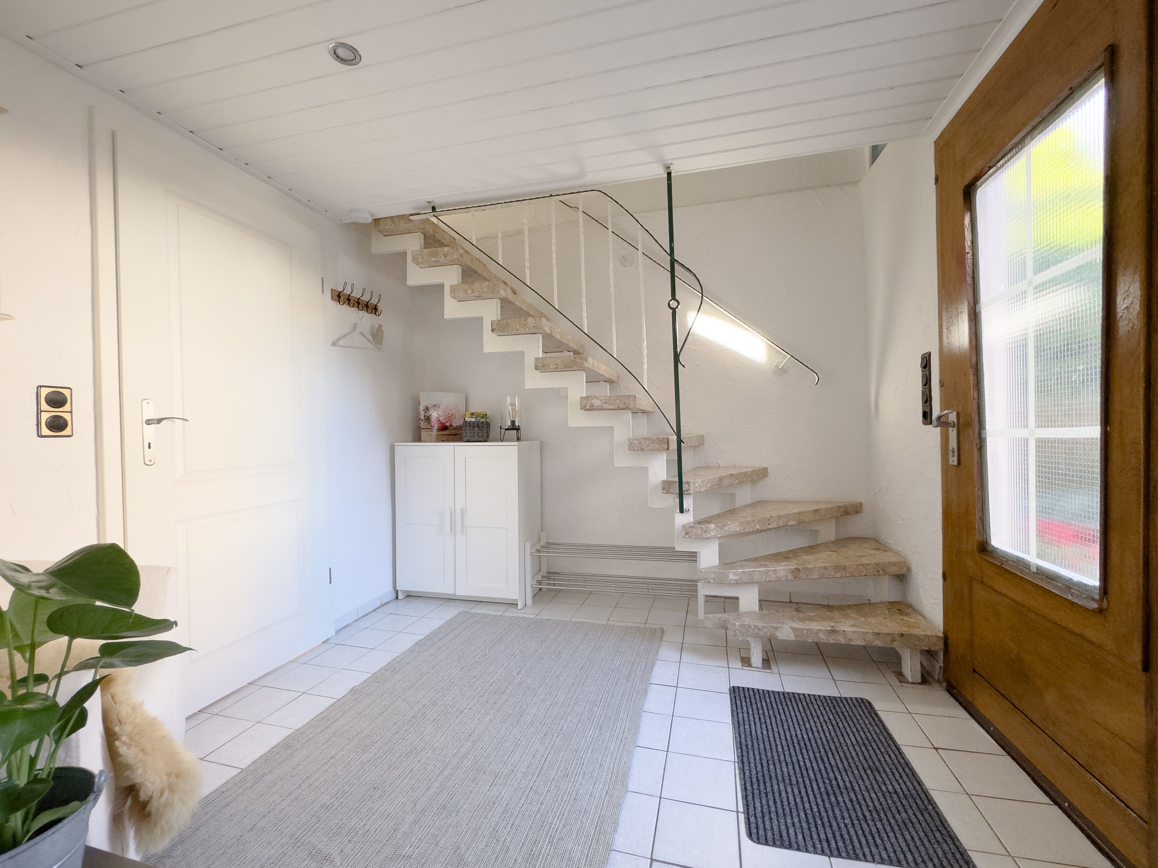 Una escalera con paredes blancas y una puerta de madera.