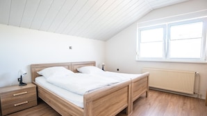 Ein Schlafzimmer mit einem Holzbett, einem Nachttisch, einer Nachttischlampe, einem Fenster und einer Heizung.
