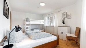 Un dormitorio con literas, un escritorio, una silla y una ventana con cortinas.