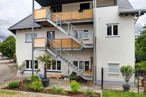 Un edificio residencial de varios pisos con escaleras, balcones y plantas en el exterior.