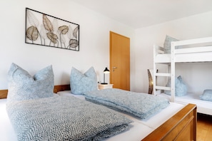 Une chambre avec un lit superposé, une table de chevet avec une lampe et une œuvre d’art murale.
