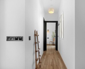 A hallway with a wooden floor, a black door at the end, and a hanging light fixture. - Girasol | Golf views - pool - terrace (Mijas Costa)
