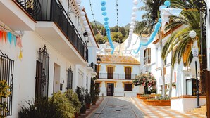 A narrow street lined with white buildings, balconies, and potted plants. - Santangelo | Sea views - terrace - pool (Benalmádena)
