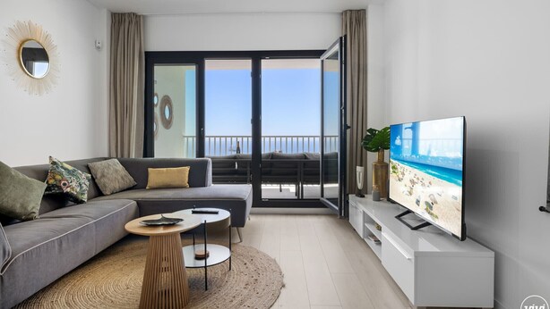 A modern living room with a sofa, coffee table, TV, and a balcony with a view. - Santangelo | Sea views - terrace - pool (Benalmádena)