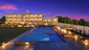 A modern hotel with a swimming pool, outdoor seating, and well-lit pathways. - Lemon Tree Resort, Somnath (Veraval)