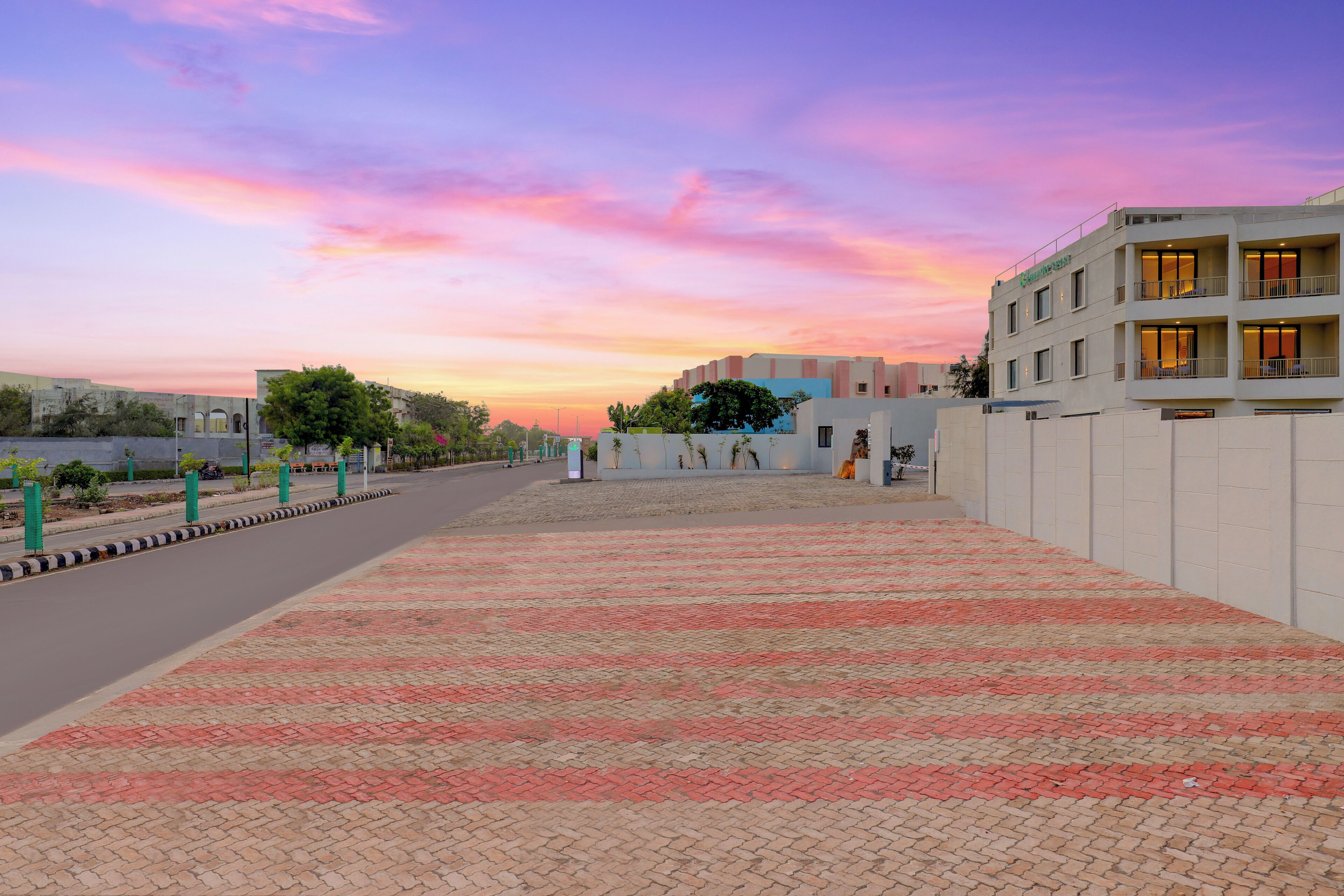A hotel with a paved walkway, a clear sky, and a building with balconies.