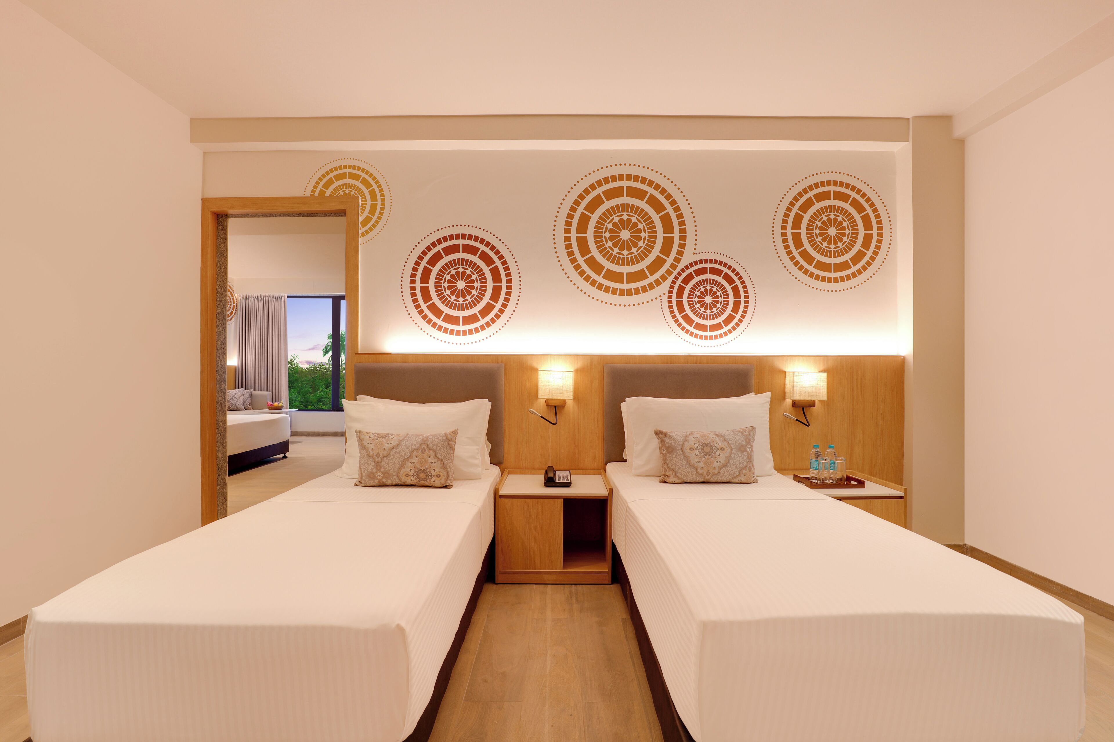 A hotel room with two beds, a wooden headboard, and a view of the outdoors.